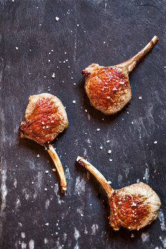 Three lamb chops and sea salt on slate