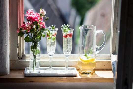 Two Champagne glasses of may wine with raspberries on window sill