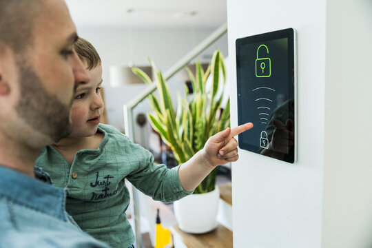 Father and son use a smart home security tablet indoors