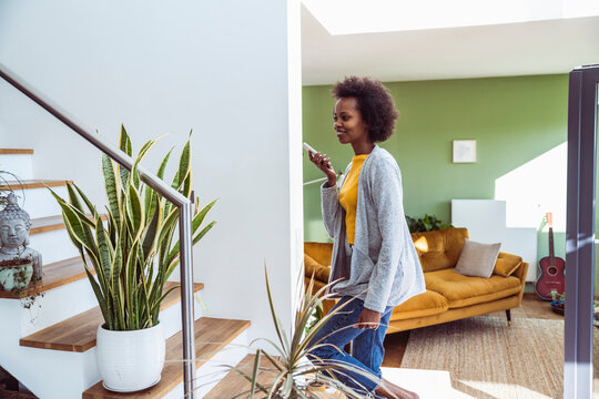 Smiling woman walks up stairs at home recording a voice message