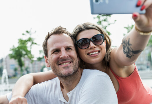 A happy couple takes a selfie with a smartphone outdoors