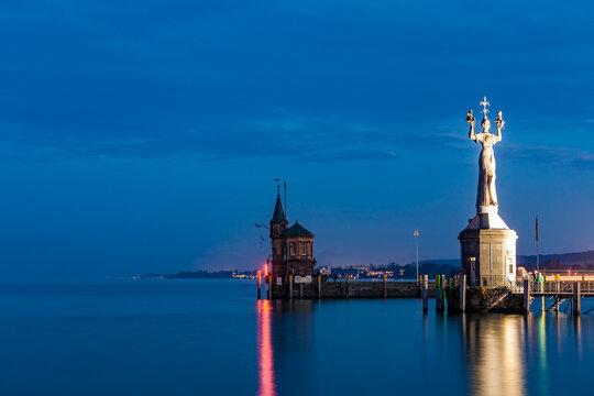 Germany, Constance, view to port entrance with lighthouse and Imperia at twilight