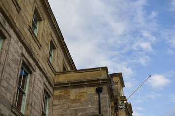 Fototapeta premium Low angle view of a historic sandstone building facade with sash windows against a blue sky with copy space, traditional British architecture