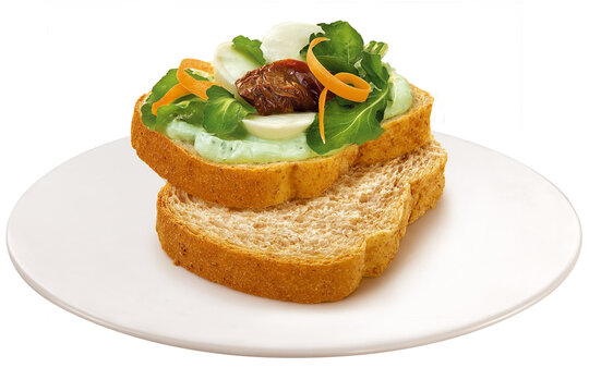 Healthy whole-wheat sandwich with spread, arugula, carrot, and sun-dried tomato on a white plate, isolated on a transparent background.
