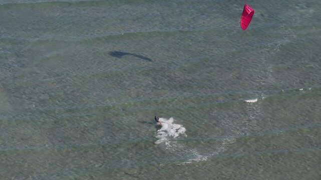 Aerial drone view of kite surfers riding the waves at My Hoa Beach in Vinh Hai, Khanh Hoa, Vietnam, showcasing a spectacular coastal landscape under bright sunlight. 