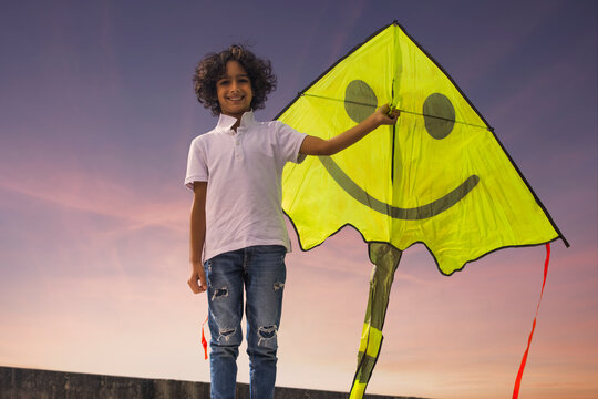 Boy standing on roof terrace with holding a kite
