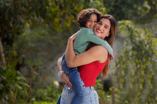 Happy woman lifting and hugging her son in the park