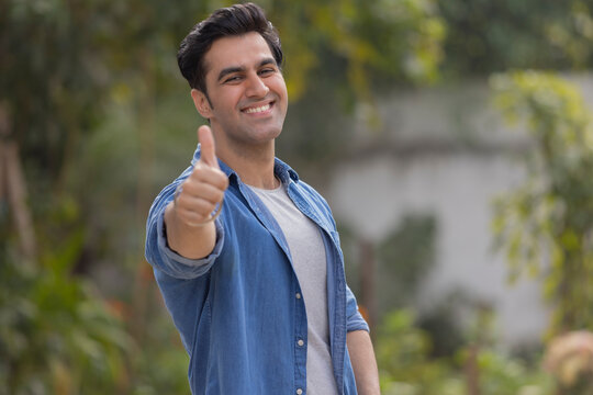 Portrait of a happy man showing his thumb while standing in the park