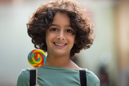 Portrait of a child boy holding a colourful big lollipop