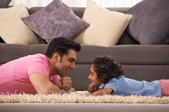 Father and Son lying down on carpet facing each other in living room