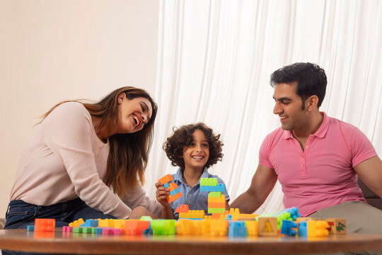Parent and son playing together with toy blocks 