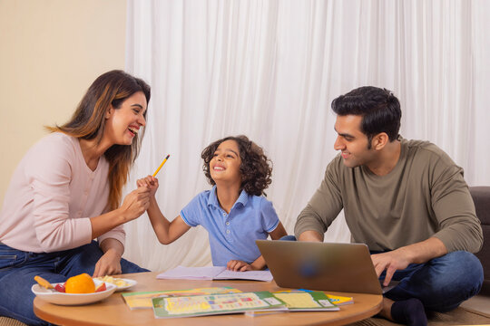 Mother kidding with her son and father using laptop