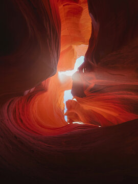 Intense sunlight bursts through sculpted red sandstone walls inside a narrow slot canyon, highlighting flowing textures and creating a spectacular desert scene for travel campaigns.