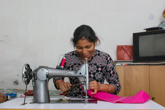 happy woman working on sewing machine as tailor