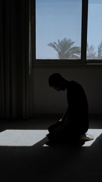 Defeated man silhouette sitting on knees with head down, feeling powerless and losing hope after difficult life struggle at home, vertical video