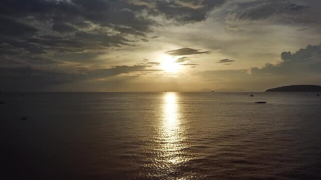 Aerial view of the sun setting over the calm waters of the Andaman Sea near Railay Beach in Ao Nang, Krabi, Thailand.