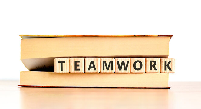Teamwork word symbol. Concept word Teamwork on beautiful wooden blocks in beautiful book. Beautiful wooden table white background. Business support help teamwork word concept. Copy space.