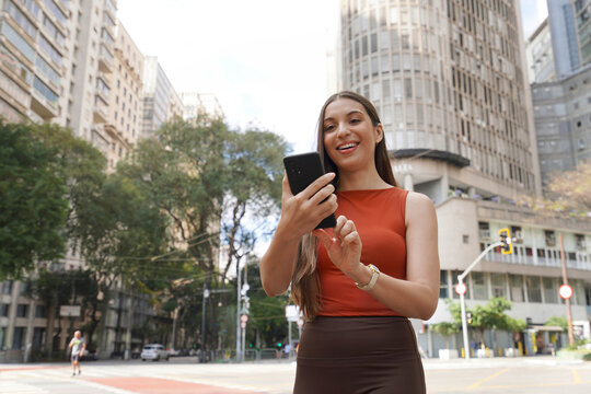 Brazilian woman using smartphone on sunny day in Republica Square, Sao Paulo, Brazil