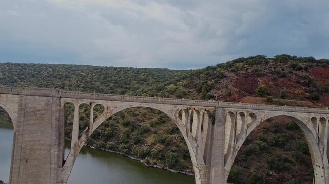 Aerial drone view of an old stone viaduct over a river in Spain