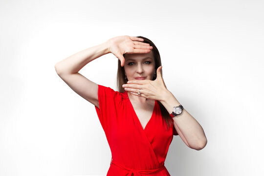 Young girl in red dress showing frame gesture isolated on white background.