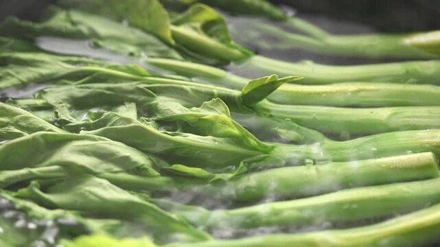 Blanching baby Chinese kale in boiling water.