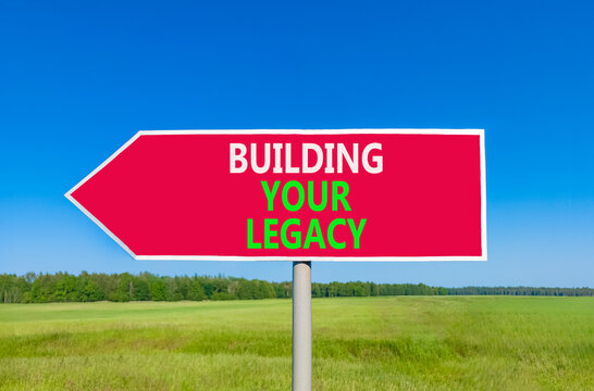 Building your legacy words symbol. Concept words Building your legacy on beautiful red road sign. Beautiful blue sky green grass background. Business building your legacy concept. Copy space.