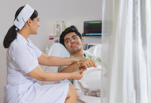 NURSE IN THE ROLE OF A SISTER TYING RAKHI TO THE BOY ADMITTED IN THE HOSPITAL