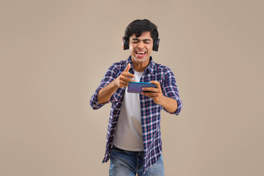 AN ENTHUSIASTIC TEENAGER HAPPILY PLAYING VIDEO GAMES ON MOBILE PHONE