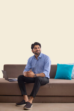 PORTRAIT OF A YOUNG PROFESSIONAL SITTING WITH LAPTOP