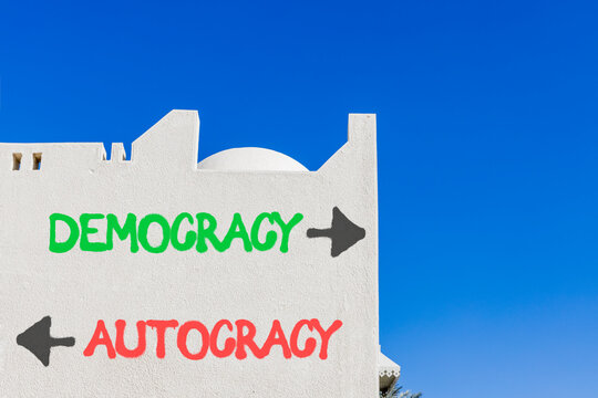 Democracy or autocracy words symbol. Concept words Democracy Autocracy on beautiful white wall. Beautiful blue sky background. Business democracy autocracy concept. Copy space