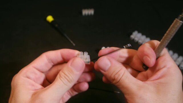 Competent technician connecting electrical wires into a transparent terminal strip connector using a small screwdriver, demonstrating a secure and professional wiring installation process