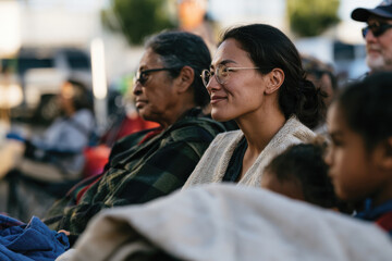 Obraz premium A peaceful scene of friends engaging in conversation outdoors, wrapped in warm blankets, showcasing connections and reflections in a cozy, vibrant environment.