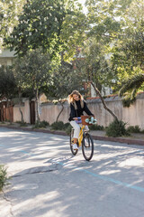 Naklejka premium Young blonde woman cycling through beautiful streets on a sunny day