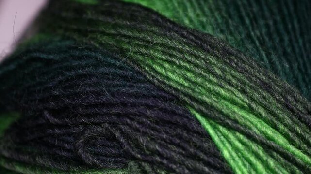 Detailed view of knitted yarn in green and black colors. Rotating in a circle