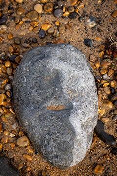 Looking down at a rock appearing to look like a face, on a beach in summer