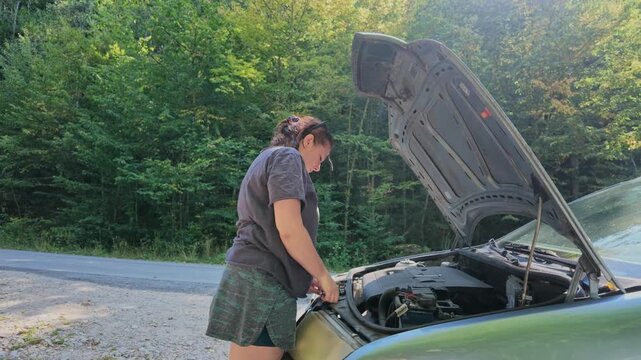Woman Trying to Repair Her Car by the Roadside Near Forest Today