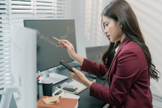 A businesswoman is analyzing stock trading charts on a computer screen in an office; the image shows a female investor analyzing data and working with the cryptocurrency exchange market.