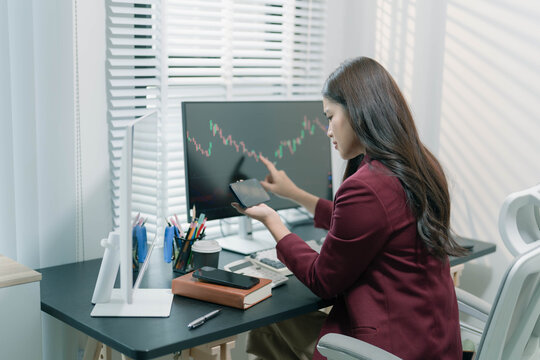A businesswoman is analyzing stock trading charts on a computer screen in an office; the image shows a female investor analyzing data and working with the cryptocurrency exchange market.