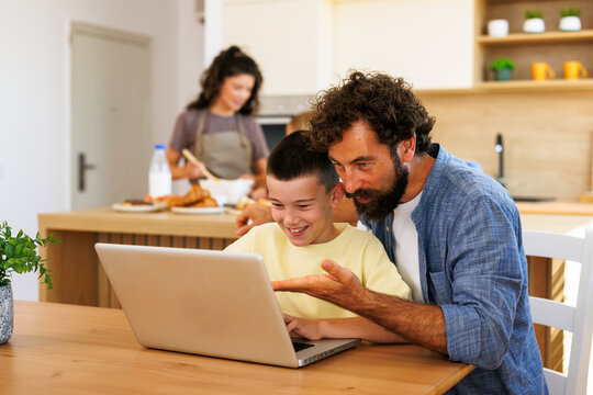 Father and son studying together on laptop