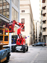 Red articulated boom lift parked on European city street during building maintenance. concept for aerial work platform rental service website, construction safety guides or urban development banner © Margarita Vais 