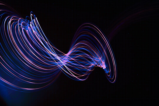 Abstract light trails create dynamic wave patterns on a dark