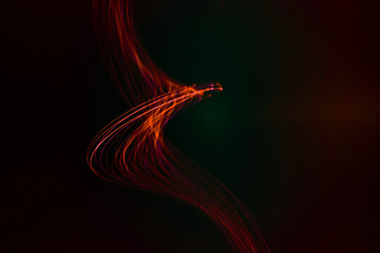 Curved red light trails create dynamic abstract patterns with long