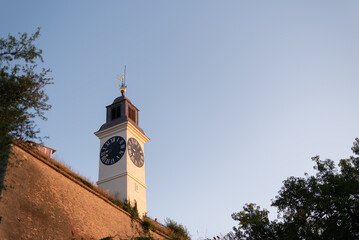 Historic clock tower of Petrovaradin Fortress stands against a clear blue sky. Novi Sad, Serbia © Denis Renkas