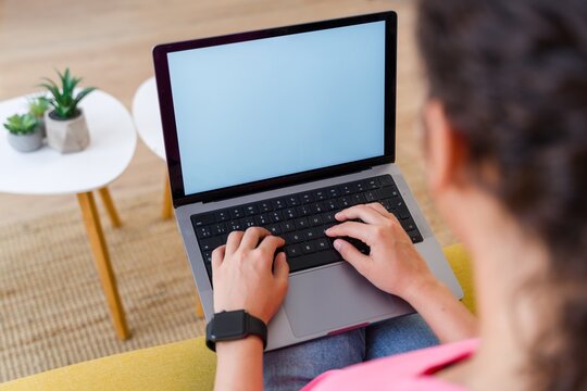 Hispanic Person typing on a laptop indoors with plants on a small