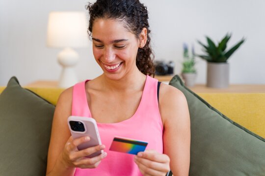 A Hispanic woman uses a smartphone and credit card for online payment