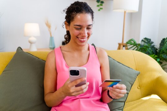 A Hispanic woman uses her smartphone and credit card for online