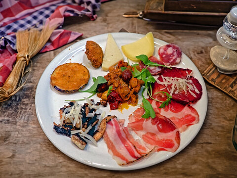 Piatto di antipasto misto tradizionale italiano con salumi, formaggi e verdure su tavolo di legno rustico 1546
