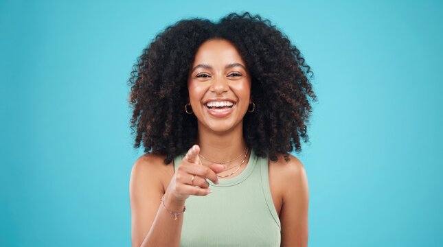 Happy young woman with afro winks and points forward with a cheerful expression