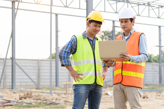 Builder engineer and supervisor consultant inspection job plan  concept, Asian contractor and foreman looking blueprint in computer laptop and checking process plan of factory warehouse construction