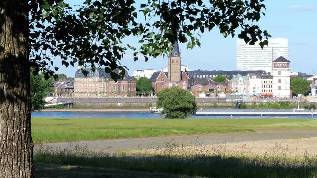 Scenic view of D&uuml;sseldorf skyline and Rhine river with green trees in the foreground on a sunny day